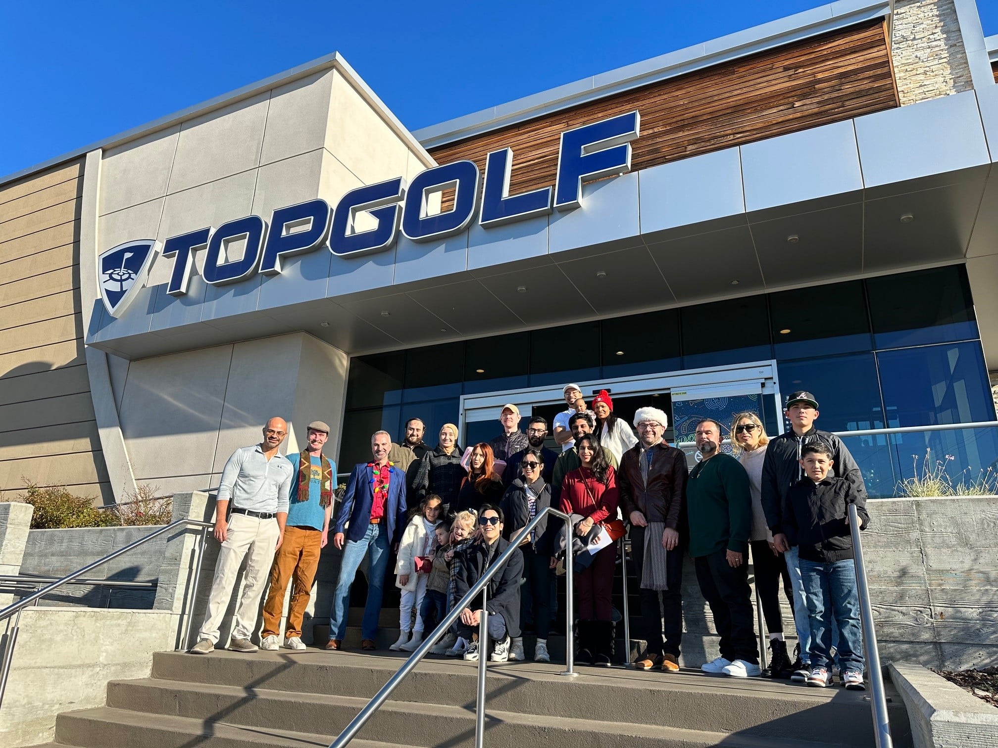 a group of people take a silly photo in front of Topgolf