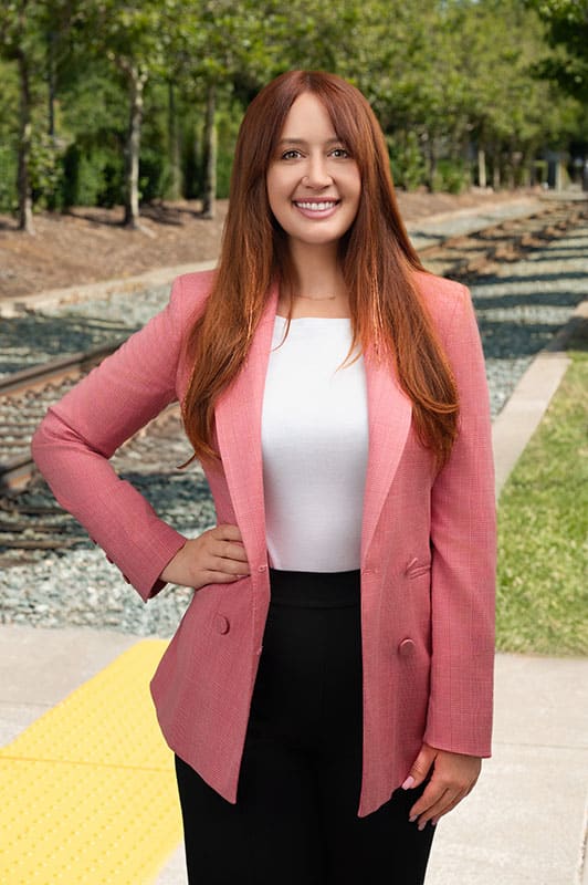 Katie Naster poses for headshot in pink blazer