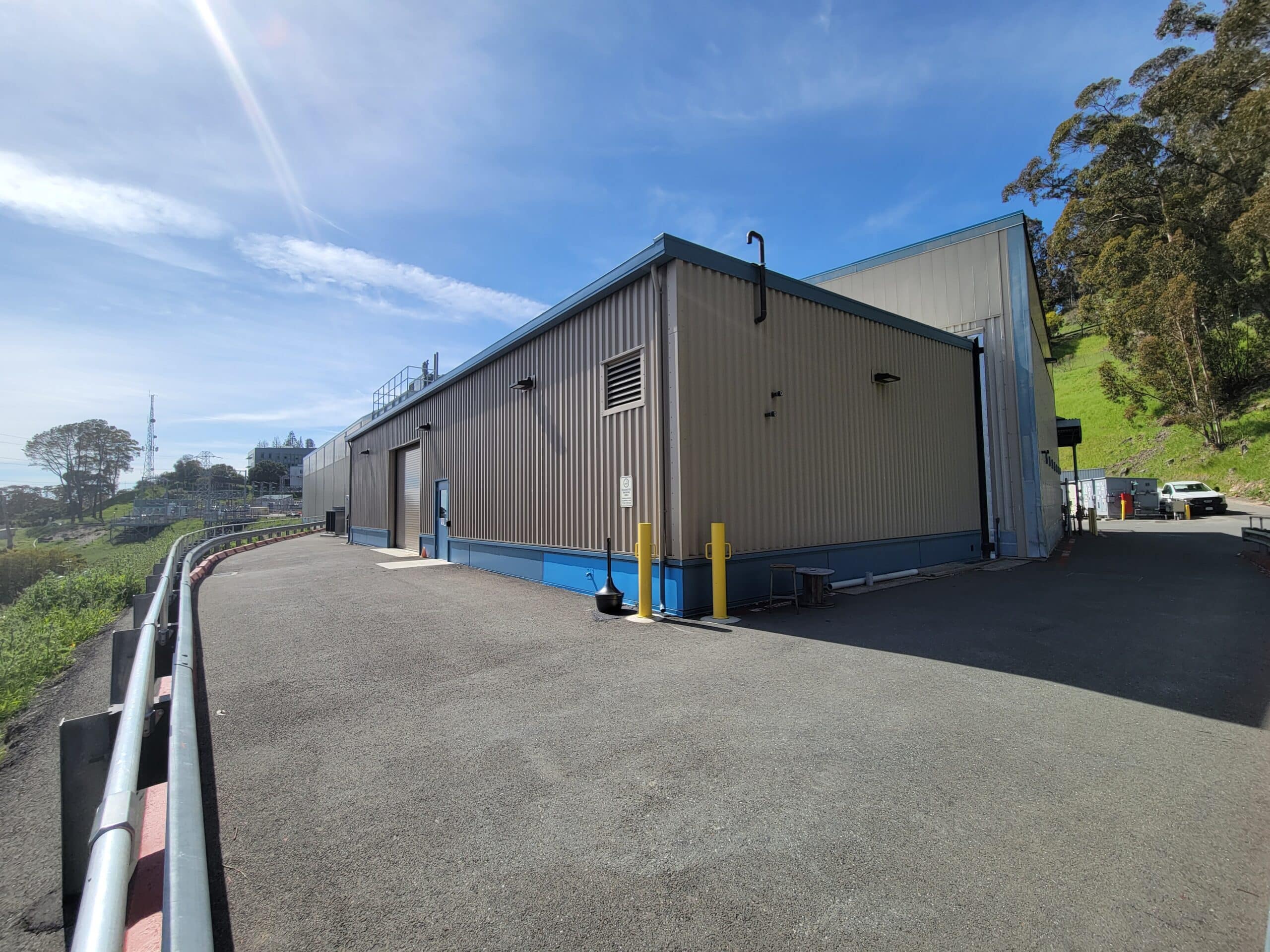 tan building with blue trim on the side of a small hill