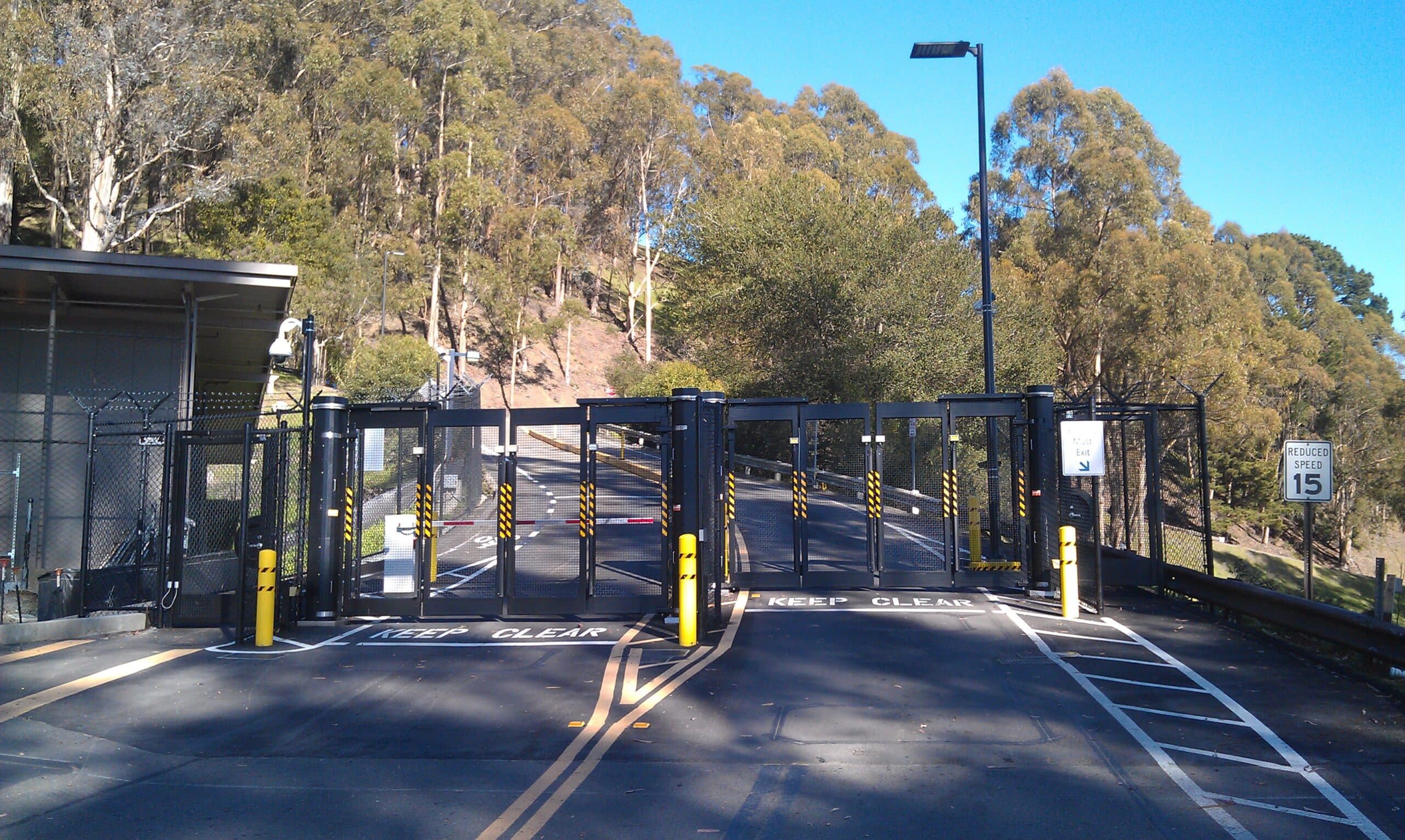 a two-lane road leading to secured black gates