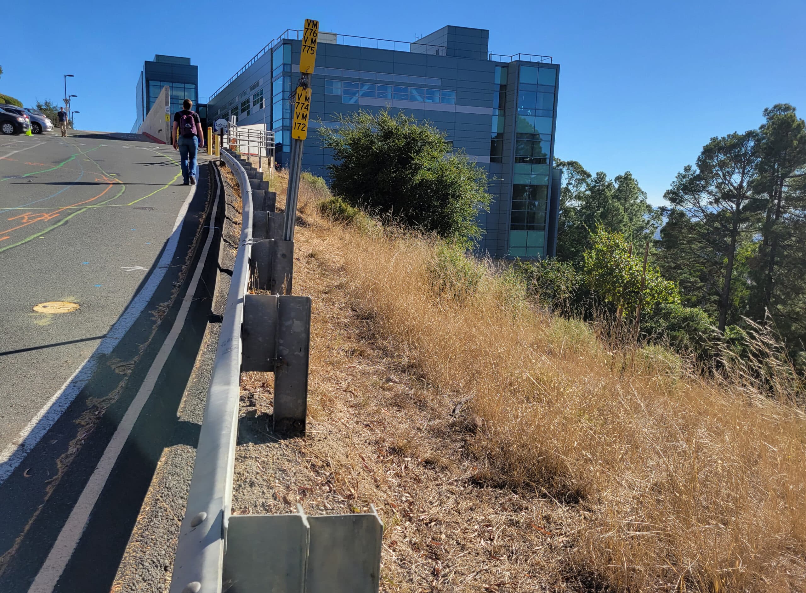 student walks up steep hill towards campus building